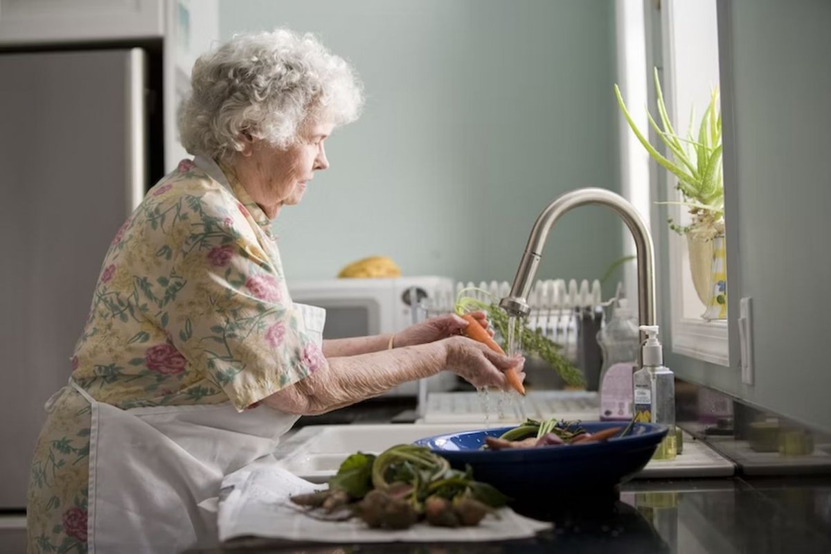 пожилая женщина моет овощи